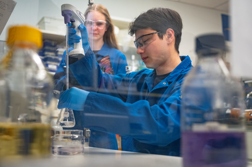 Two people in lab coats working together in a lab.
